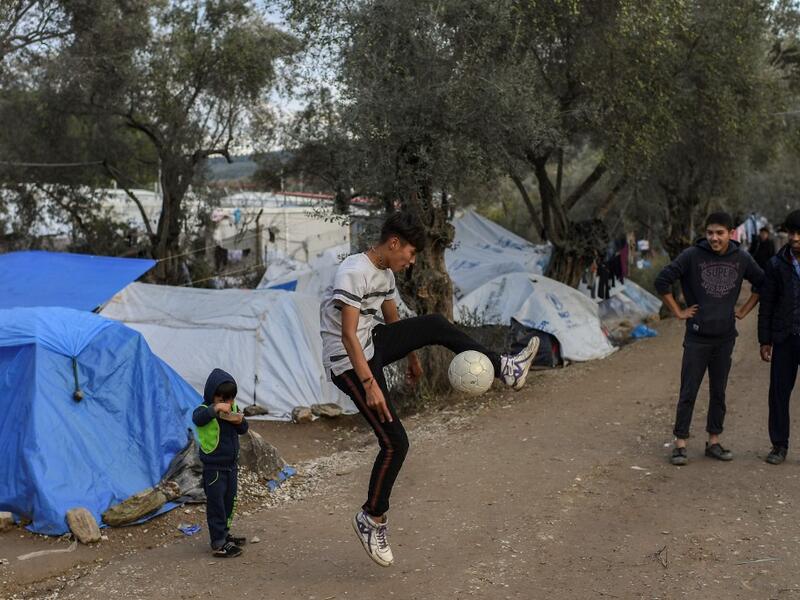 Children play with a ball at a makeshift camp outside the overcrowded Moria camp near the capital Mytilene in the island of Lesbos on November 28, 2019. Conditions remain difficult in the overcrowded camp in Greece with winter fast approaching. ARIS MESSINIS / AFP