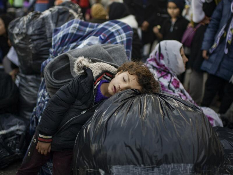 A child rests on bags as migrants and refugees wait to depart from the Greek island camp of Moria on Lesbos to Athens on November 29, 2019.ARIS MESSINIS / AFP