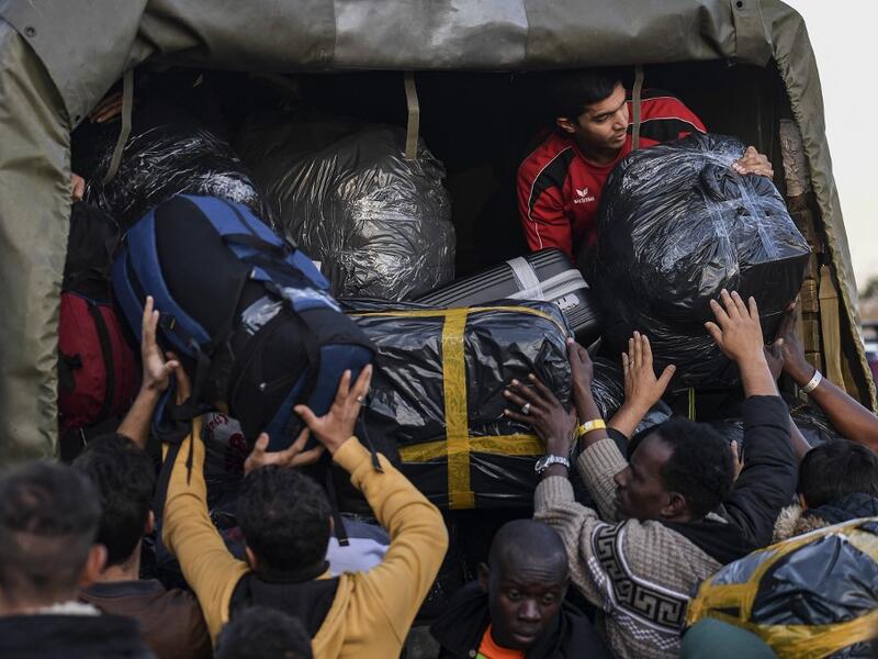Refugees and migrants load their belongings onto a truck as they depart from the Greek island camp of Moria on Lesbos to Athens on November 29, 2019. Conditions remain difficult in the overcrowded camp counting over 18,000 people with winter fast approaching. Last week the government announced it will shut down the three largest of its overcrowded migrant camps on islands facing Turkey, and replace them with new closed facilities with much larger capacity. ARIS MESSINIS / AFP