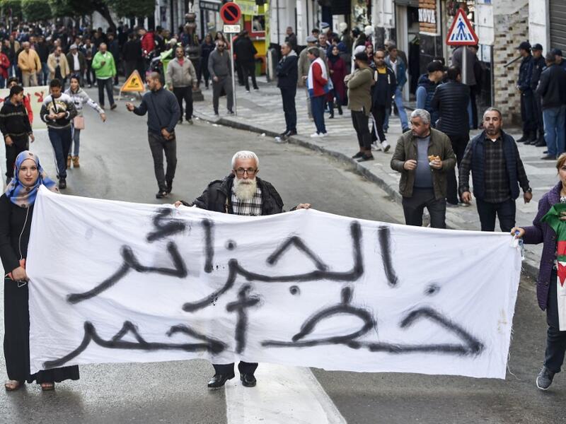 People march with a large banner reading in Arabic "Algeria is a red line" during a demonstration in the centre of the capital Algiers on November 30, 2019, in support of the upcoming presidential vote scheduled to take place in less than two weeks. (RYAD KRAMDI / AFP)