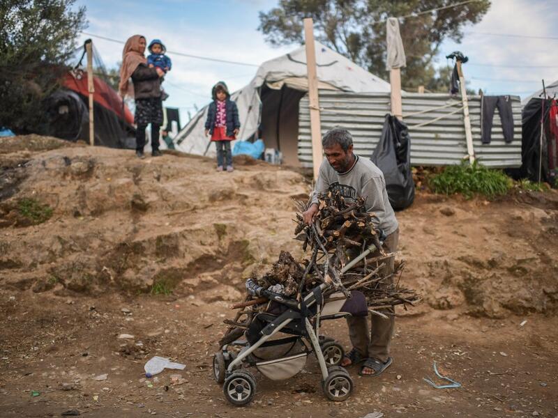 A man unloads firewoods from a baby troller at a makeshift camp next to the camp of Moria in the island of Lesbos on November 30, 2019. Conditions remain difficult in the overcrowded camp counting over 18.000 people with winter fast approaching. ARIS MESSINIS / AFP