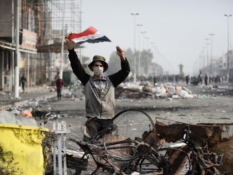An Iraqi demonstrator carries the national flag in the southern Iraqi Shiite holy city of Najaf (AFP)