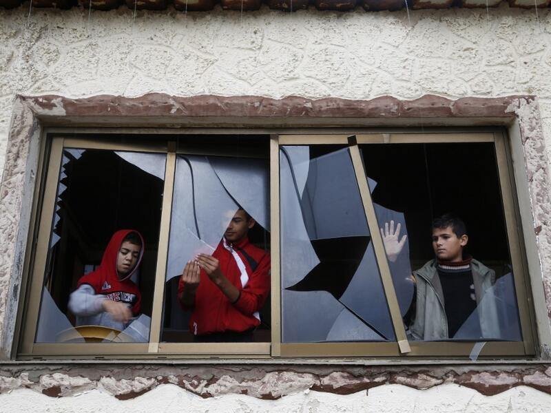 Palestinian boys pull shards of glass from a broken window at their home near the site of Israeli overnight attacks in Gaza City on December 8, 2019. (AFP/ File Photo)