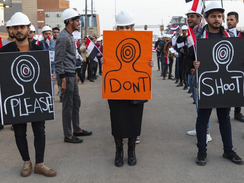 Iraqi protesters wearing protective helmets carry placards during a rally near the local government headquarters in the southern city of Basra on December 13, 2019, as they take part in ongoing anti-government demonstrations. (AFP/ File Photo)