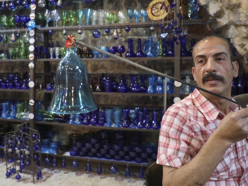A Palestinian craftsman shapes molten glass into a Christmas ornament at his workshop in the southern West Bank city of Hebron, on December 15, 2019. HAZEM BADER / AFP