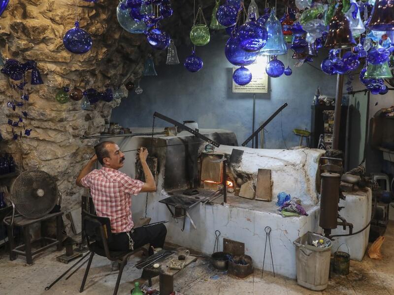 A Palestinian craftsman shapes molten glass into Christmas ornaments at his workshop in the southern West Bank city of Hebron, on December 15, 2019. HAZEM BADER / AFP