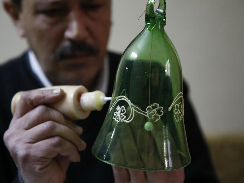 A Palestinian craftsman decorates a glass Christmas ornament at a workshop in the southern West Bank city of Hebron, on December 15, 2019. HAZEM BADER / AFP