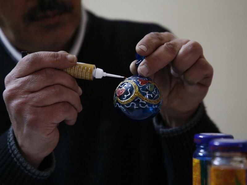 A Palestinian craftsman decorates a glass Christmas ornament at a workshop in the southern West Bank city of Hebron, on December 15, 2019. HAZEM BADER / AFP