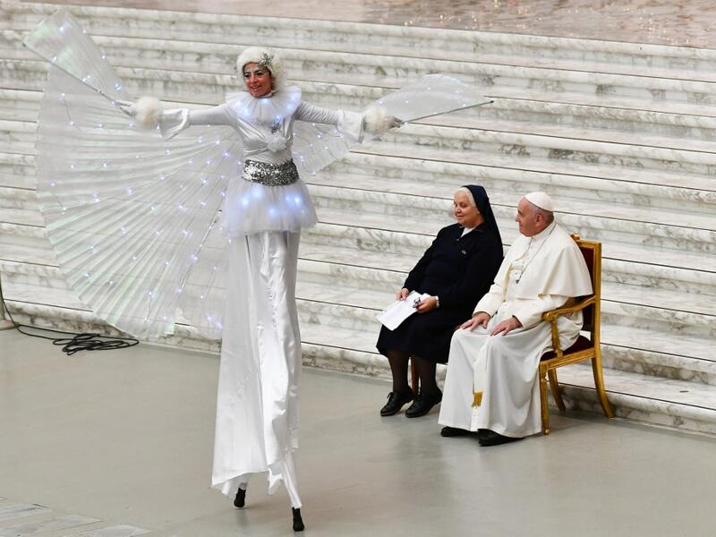 Pope Francis and Suor Antonietta Collacchi, director of the Santa Marta dispensary, look at a performer on stilts during an audience for children and families of the Santa Marta dispensary on December 22, 2019 at Paul-VI hall in the Vatican. Vincenzo PINTO / AFP