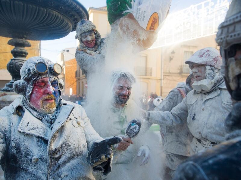 A reveller dressed in mock military garb empties out a sack of flour over a journalist during the "Els Enfarinats" battle in the southeastern Spanish town of Ibi on December 28, 2019. During this 200-year-old traditional festival participants known as Els Enfarinats (those covered in flour) dress in military clothes and stage a mock coup d'etat as they battle using flour, eggs and firecrackers outside the city town hall as part of the celebrations of the Day of the Innocents, a traditional day in Spain for 