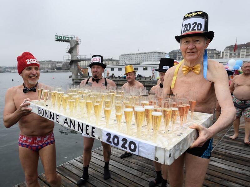 Participants celebrate during a New Year's traditional bathe at Lake Geneva in Geneva on January 1, 2020, where some 70 swimmers braved the 7degree celsius waters of the lake to take part in the event. FABRICE COFFRINI / AFP