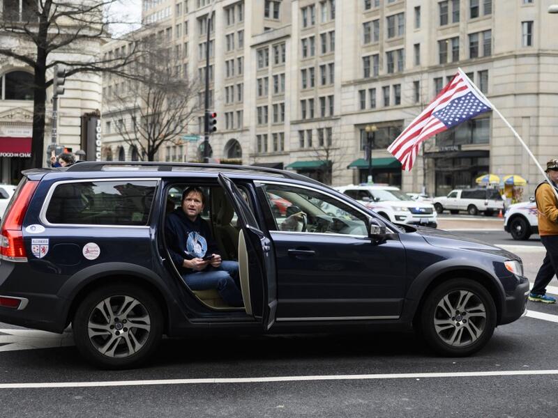 A man watches from a car as anti-war activist demonstrate outside the Trump International Hotel in Washington, DC, on January 4, 2020.ANDREW CABALLERO-REYNOLDS / AFP