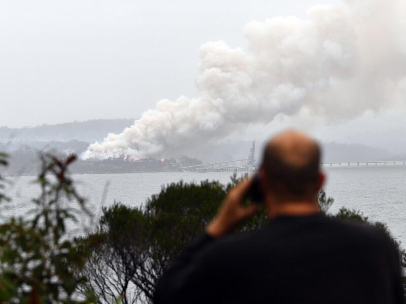 Smoke raises to the sky as a woodchip mill burns in Eden, in Australia's New South Wales state on January 6, 2020. January 5 brought milder conditions, including some rainfall in New South Wales and neighbouring Victoria state, but some communities were still under threat from out-of-control blazes, particularly in and around the town of Eden in New South Wales near the Victorian border. SAEED KHAN / AFP