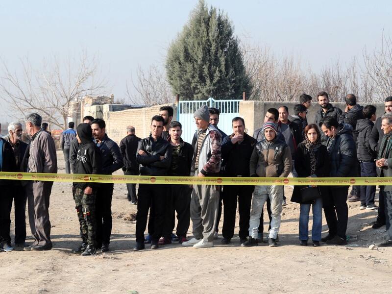 Bystanders watch from a behind a cordon as rescue teams work after a Ukrainian plane carrying 176 passengers crashed near Imam Khomeini airport in the Iranian capital Tehran early in the morning on January 8, 2020, killing everyone on board. The Boeing 737 had left Tehran's international airport bound for Kiev, semi-official news agency ISNA said, adding that 10 ambulances were sent to the crash site. AFP