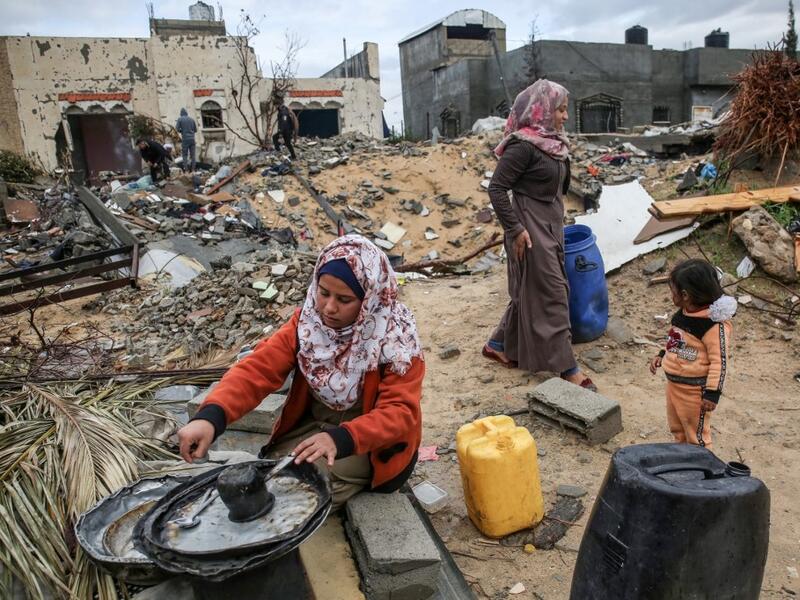 A Palestinian woman carries washes the dishes outside her shack in Khan Yunis in the southern Gaza Strip on January 10, 2020. A family of 17, whose house was destroyed by an Israeli air strike last November, now live in a shack in cold weather and heavy rain. SAID KHATIB / AFP
