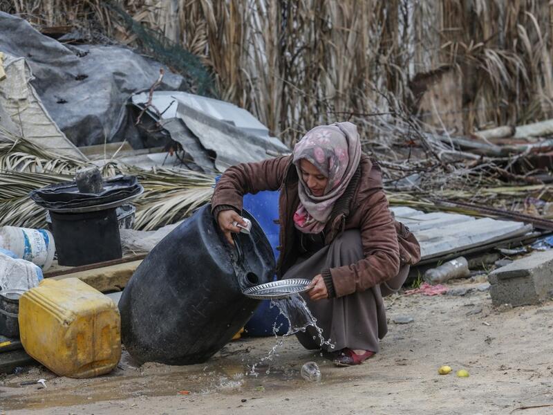A Palestinian woman carries washes the dishes outside her shack in Khan Yunis in the southern Gaza Strip on January 10, 2020. A family of 17, whose house was destroyed by an Israeli air strike last November, now live in a shack in cold weather and heavy rain. SAID KHATIB / AFP