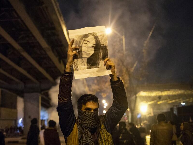 An Iranian man holds a picture of a victim of the Ukrainian Boeing 737-800 plane crash during a demonstration in front of Tehran's Amir Kabir University on January 11, 2020. Demonstrations broke out for a second night in a row after Iran admitted to having shot down a Ukrainian passenger jet by mistake on January 8, killing all 176 people on board. STR / AFP