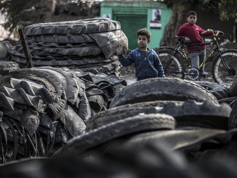 Children stand before piles of tyres at a rubber recycling workshop in the village of Mit al-Harun in Egypt's central Nile delta Gharbia Governorate, about 70 kilometres (43 miles) north of the capital, on January 14, 2020. Khaled DESOUKI / AFP