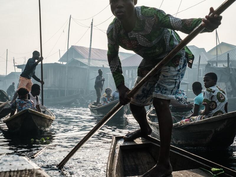 A picture taken on March 2, 2019 shows people steering boats on a waterway in the Makoko waterfront community in a polluted lagoon in Lagos, Africa’s biggest megalopolis in Nigeria. The sprawling community began in the 19th century as a fishing village for immigrants who settled on the water's edge. As more arrived and land became rare, people started to move out onto the water. Over time, Makoko became a floating realm of perhaps a quarter of a million people, although the real number is anyone's guess. YA