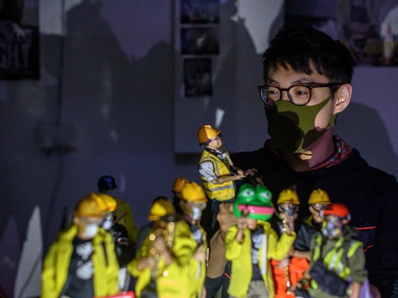 This picture taken on January 14, 2020 shows figurine enthusiast Charlie, who asked to use a pseudonym, posing with 1:6 scale action figures depicting characters involved in the Hong Kong protests, following an interview with AFP in Hong Kong. Intricately detailed Hong Kong protester figurines have become the latest must-have collectables as toy stores recreate the pro-democracy movement's street battles with police in their shop displays.  Philip FONG / AFP