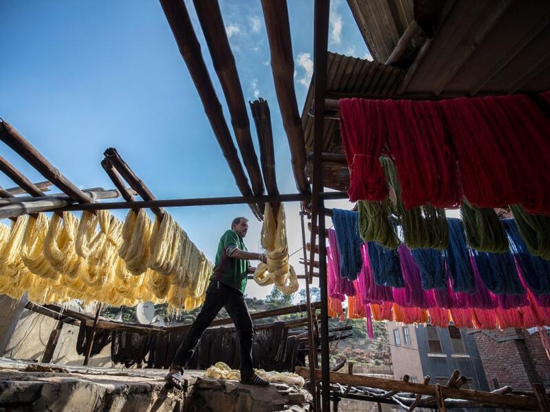 Mohamed Kamal, a 59-year-old dye worker, hangs dyed yarns out to dry in the sun at a traditional hand-dying workshop in the Egyptian capital Cairo's centuries old district of Darb al-Ahmar on January 21, 2020. Khaled DESOUKI / AFP