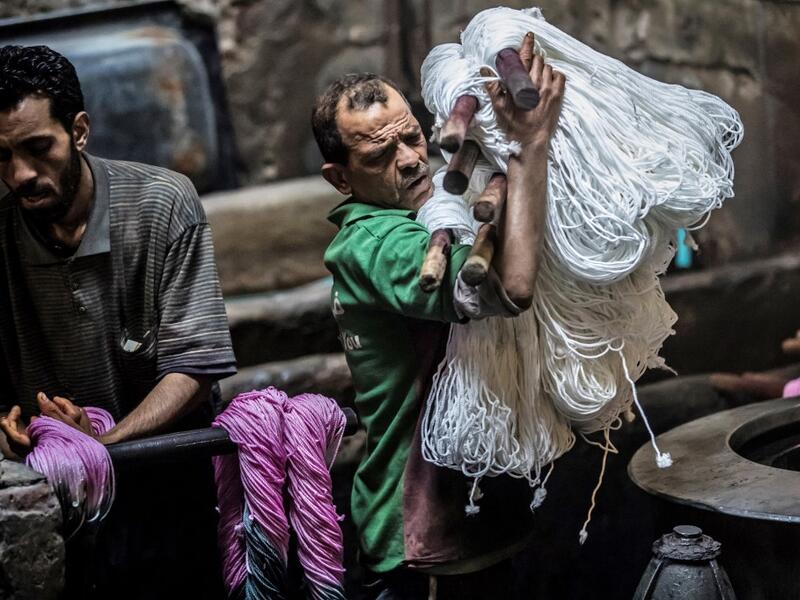 A worker carries undyed yarns to be processed at a traditional hand-dying workshop in the Egyptian capital Cairo's centuries old district of Darb al-Ahmar on January 21, 2020. Khaled DESOUKI / AFP