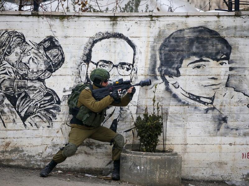 An Israeli soldier fires teargas towards Palestinian demonstrators during a demonstration in al-Aroub Palestinian refugee camp, between the West Bank towns of Hebron and Bethlehem, on January 29, 2020. US President Donald Trump unveiled his controversial Israeli-Palestinian peace deal that staunchly favours Israel but offers Palestinians a pathway to a limited state. HAZEM BADER / AFP