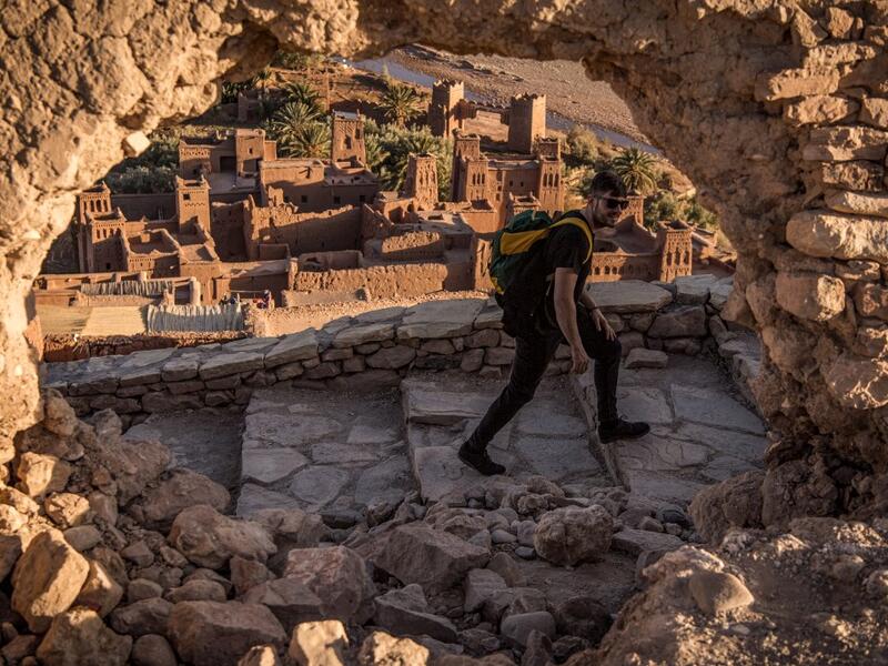 A tourist walks near the Kasbah (ancient fortress) of Ait-Ben-Haddou (background), where scenes depicting the fictional city of Yunkai from the hit HBO television series "Game of Thrones" were filmed, about 32 kilometres northwest of the city of Ouarzazate south of Morocco's High Atlas mountains on January 27, 2020. FADEL SENNA / AFP