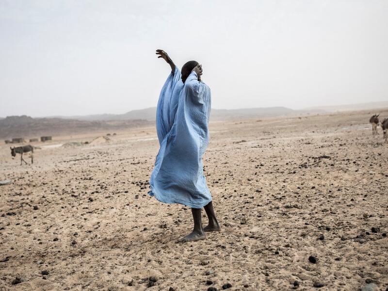 A man gestures to his family at the Touijinit Camp along the caravan route from Tichitt to Aratane in Mauritania on January 25, 2020. In the arid West African country of Mauritania, the way of life of the traditional group of hunters known as the Nemadi is slowly disappearing. JOHN WESSELS / AFP