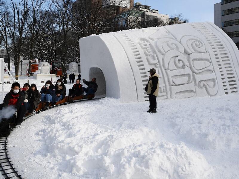 People ride a mini steam locomotive through the "Cup Noodles and Rui Hachimura's snow tunnel" during the Sapporo Snow Festival on February 4, 2020. The snow festival, which opened January 31 in the capital of Hokkaido in northern Japan, is a major draw for the region, attracting more than 2.7 million visitors last year. Organisers for this year's festival were forced to truck in an unprecedented amount of extra powder to build their signature sculptures after an unseasonably warm winter.  CHARLY TRIBALLEAU 
