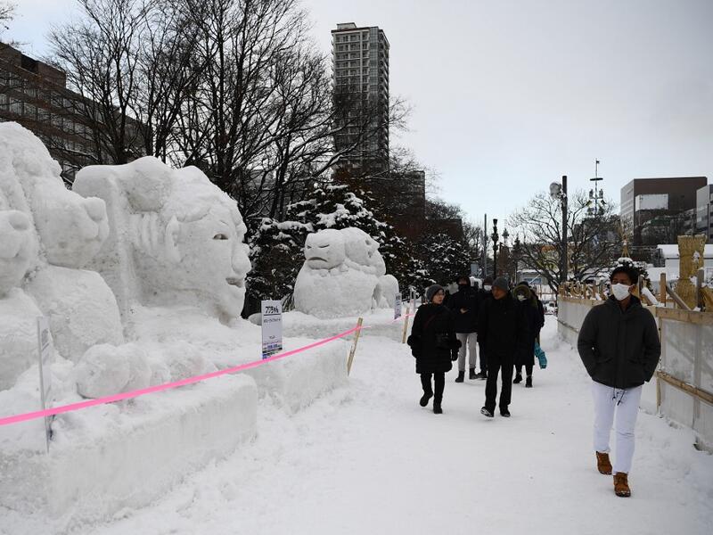 People visit the Sapporo Snow Festival in Sapporo on February 4, 2020. The snow festival, which opened January 31 in the capital of Hokkaido in northern Japan, is a major draw for the region, attracting more than 2.7 million visitors last year. Organisers for this year's festival were forced to truck in an unprecedented amount of extra powder to build their signature sculptures after an unseasonably warm winter.  CHARLY TRIBALLEAU / AFP