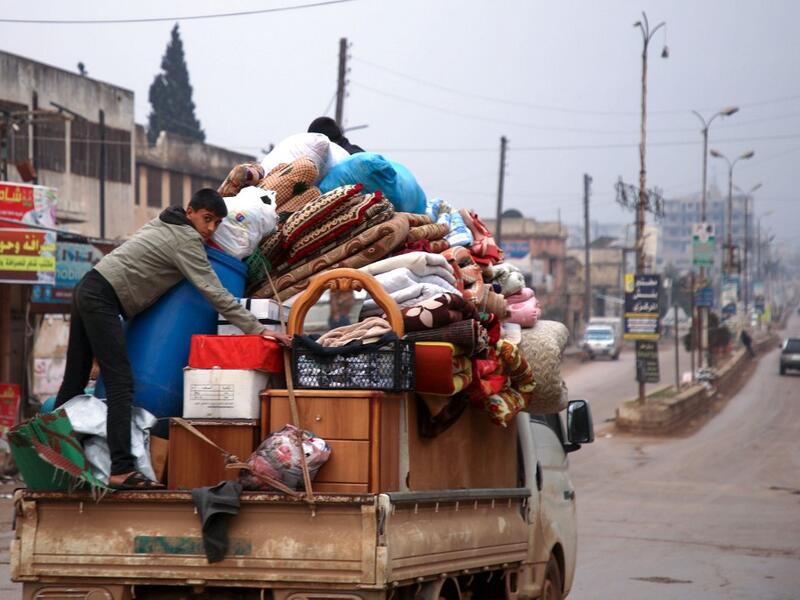 A Syrian youth climbs atop belongings in the back of a truck as people leave the town of Binnish in the northwestern province of Idlib, on February 4, 2020, amid an ongoing offensive by pro-regime forces. A Russian-backed Syrian government offensive against the country's last rebel enclave of Idlib has displaced more than half a million people in two months, according to the United Nations. The wave of displacement, which coincides with a biting winter, is one of the largest since the start of the Syrian wa
