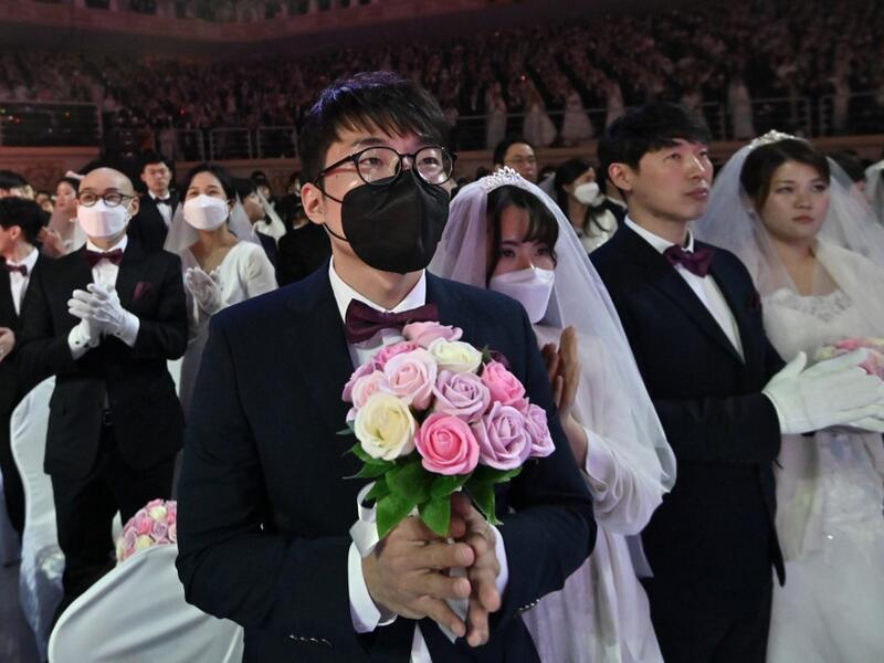 A couple wearing protective face masks attend a mass wedding ceremony organised by the Unification Church at Cheongshim Peace World Center in Gapyeong on February 7, 2020. South Korea has confirmed 24 cases of the SARS-like virus so far and placed nearly 260 people in quarantine for detailed checks amid growing public alarm. Jung Yeon-je / AFP