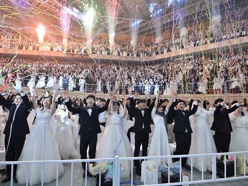 Couples cheer during a mass wedding ceremony organised by the Unification Church at Cheongshim Peace World Center in Gapyeong on February 7, 2020. Thousands of Unification Church couples married at a mass wedding to mark the eighth anniversary of the death of founder and self-proclaimed messiah Sun Myung Moon. Jung Yeon-je / AFP