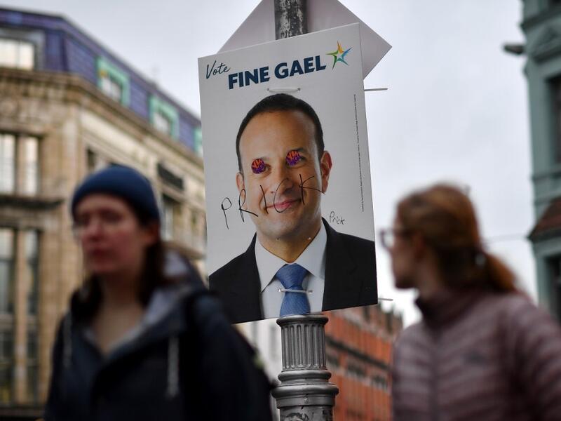 Pedestrians walk past a defaced campaign poster featuring Ireland's Prime Minister and leader of the Fine Gael party, Leo Varadkar as they walk along a street in Dublin on February 7, 2020, on the eve of the country's General Election. Ireland on Friday entered the final day of campaigning before this weekend's election, as polls predicted a historic three-way fight for control of the next government. Prime Minister Leo Varadkar, of the Fine Gael party, was canvassing in the western town of Ennis while Fianna Fail leader Micheal Martin was in his home city of Cork, in the south. Ben STANSALL / AFP Pedestrians walk past a defaced campaign poster featuring Ireland's Prime Minister and leader of the Fine Gael party, Leo Varadkar as they walk along a street in Dublin on February 7, 2020, on the eve of the country's General Election. Ireland on Friday entered the final day of campaigning before this weekend's election, as polls predicted a historic three-way fight for control of the next government. Prime Minister Leo Varadkar, of the Fine Gael party, was canvassing in the western town of Ennis while Fian