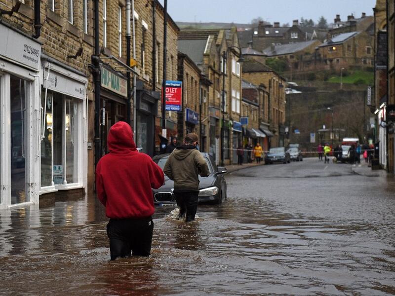 People wade through floodwater in the streets of Hebden Bridge, northern England, on February 9, 2020, as Storm Ciara swept over the country. Britain and Ireland hunkered down Sunday for a powerful storm expected to disrupt air, rail and sea links, cancel sports events, cut electrical power and damage property. With howling winds and driving rain, forecasters said Ciara would also hit France, Belgium, the Netherlands, Switzerland and Germany. Oli SCARFF / AFP
