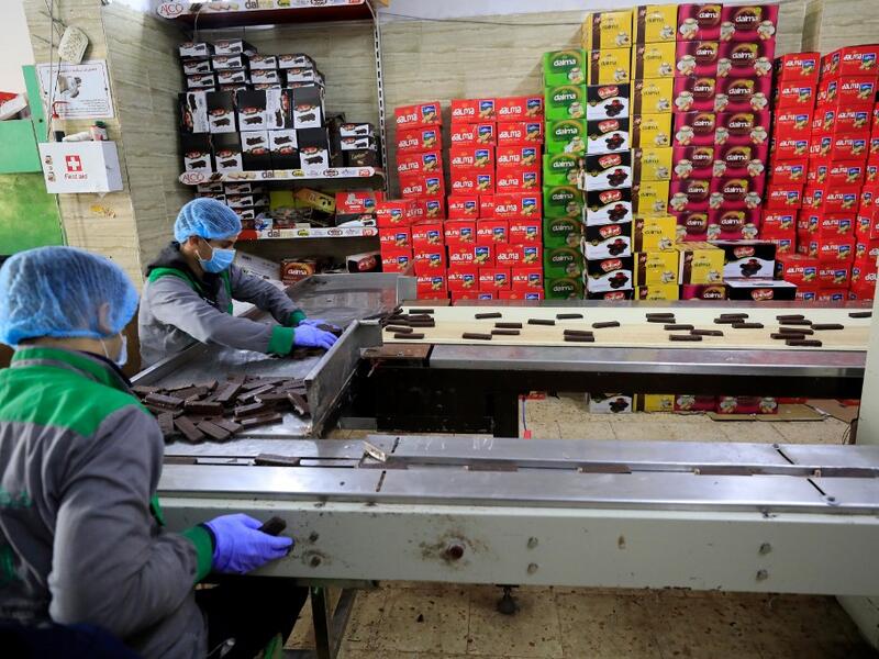 Workers at the al-Arees sweets factory sort a batch of chocolate-covered biscuits in Gaza City on February 5, 2020. Al-Arees's products are Gazan but their components are not, as few of the basic raw ingredients are produced in the impoverished Mediterranean coastal strip. Emmanuel DUNAND / AFP