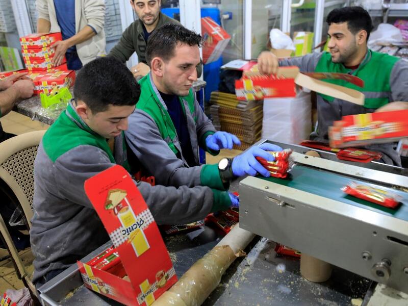 Workers pack chocolate bars at al-Arees factory in Gaza City on February 5, 2020. Al-Arees's products are Gazan but their components are not, as few of the basic raw ingredients are produced in the impoverished Mediterranean coastal strip. Israel controls all goods that enter Gaza, imposing a blockade that tightened after the tiny enclave was seized by the Islamist group Hamas in 2007. EMMANUEL DUNAND / AFP