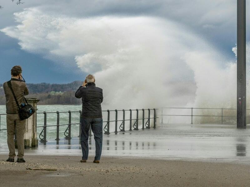 Two men take pictures of water spilling over a quay in the Eastern end of Lake Constance (Bodensee), as the storm Ciara reaches Austria, in Bregenz, Austria, on February 10, 2020. DIETMAR STIPLOVSEK / APA / AFP