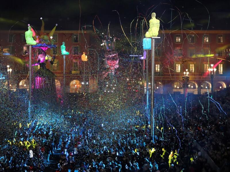 Giant figures depicting a king and a queen are seen through confetti rain during the 136th Nice Carnival parade in Nice, southeastern France, on February 15, 2020. The Carnival takes place until February 29, 2020 on the theme 'King of Fashion'. VALERY HACHE / AFP