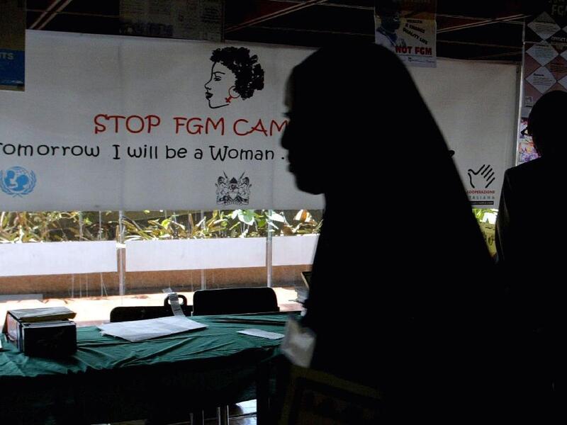 A young woman walks past a banner against female genital mutilation (AFP Photo/SIMON MAINA)