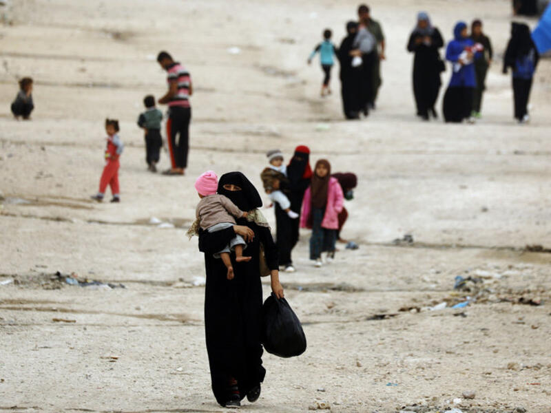 People walk through Ain Issa, one of the camps that holds displaced Syrians as well as foreign wives of ISIS fighters and their children. AFP