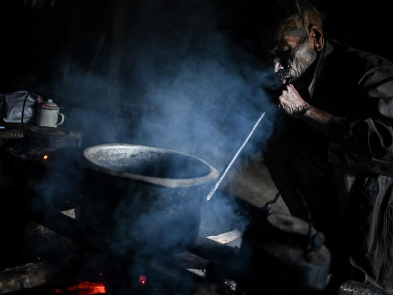 This photo taken on February 9, 2020 shows Nok Tan, 75, a tattooed Konyak tribeman, cooking in his house in a village in Sagaing region of Myanmar, wedged in a semi-autonomous zone near the Indian border. People in the region subscribe to a complex patchwork of customs, intertwining their animist beliefs with warrior traditions that include striking tattoo designs, which can signify tribal identity, life accomplishments or the completion of a rite of passage. Ye Aung THU / AFP