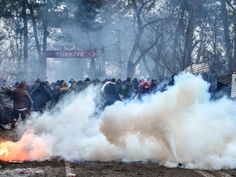 Migrants run away as Greek anti riot police officers use tears gas on the buffer zone Turkey-Greece border, at Pazarkule, in Edirne district, on February 29 , 2020. Thousands of migrants stuck on the Turkey-Greece border clashed with Greek police on February 29, 2020. Ozan KOSE / AFP