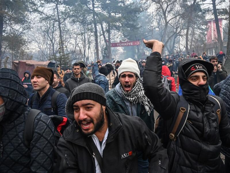 Migrants react as Greek anti-riot police officers use tears gas on the buffer zone Turkey-Greece border, at Pazarkule, in Edirne district, on February 29, 2020. Thousands of migrants stuck on the Turkey-Greece border clashed with Greek police on February 29, 2020. Ozan KOSE / AFP