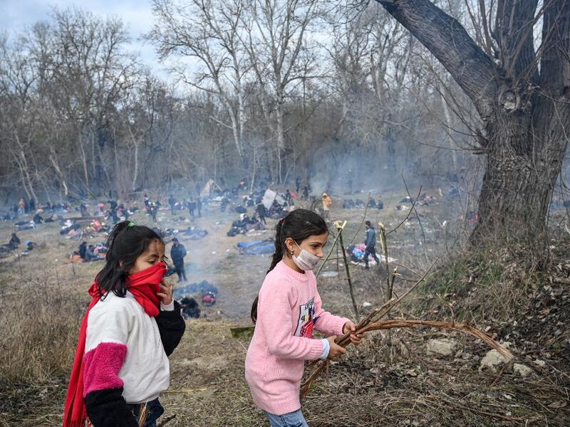 Children collect branches as migrants wait to pass the buffer zone at Turkey-Greece border at Pazarkule, in Edirne district, on February 29, 2020. Thousands of migrants stuck on the Turkey-Greece border clashed with Greek police on February 29, 2020, according to an AFP photographer at the scene.OZAN KOSE / AFP