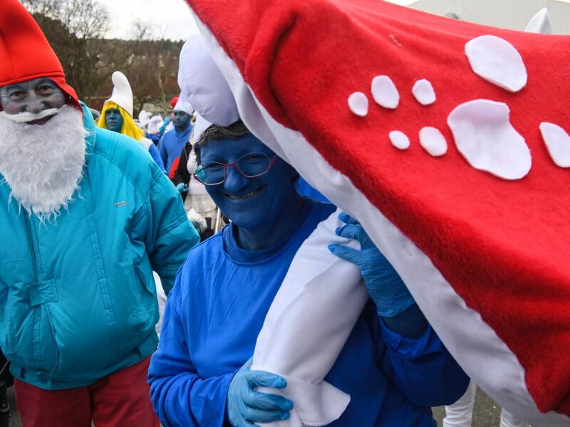 People dressed as Smurfs ('Schtroumpfs' in French), a Belgian comic franchise centered on a fictional colony of small, blue, human-like creatures who live in mushroom-shaped houses in the forest, pose for a picture as they attend a world record gathering of Smurfs on March 7, 2020, in Landerneau, western France. Damien MEYER / AFP
