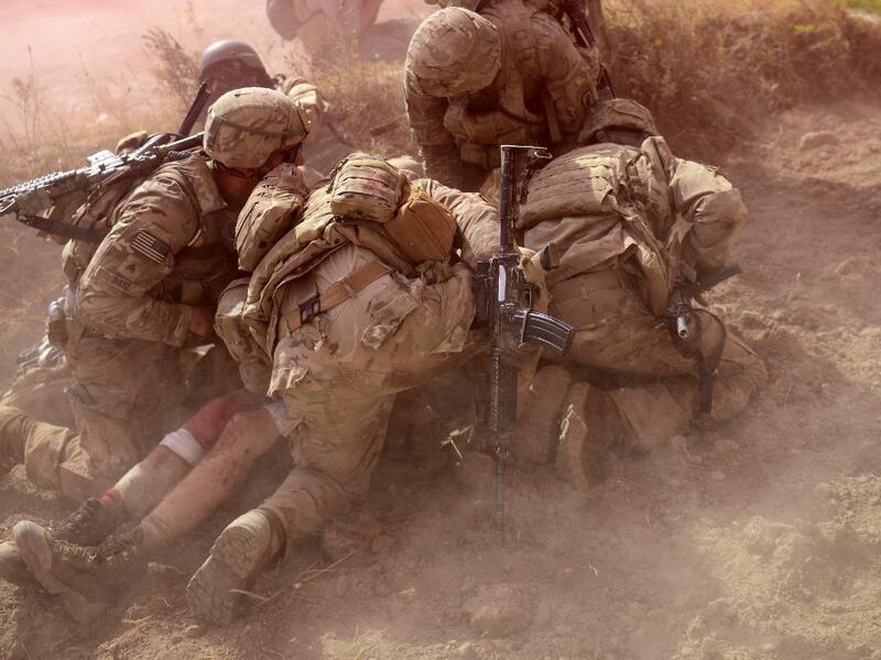 In this file photo taken on October 13, 2012, US Army soldiers attached to 2nd platoon, C troop, 1st Squadron (Airborne), 91st U.S Cavalry Regiment, 173rd Airborne Brigade Combat Team operating under NATO sponsored International Security Assistance Force (ISAF) protect a wounded comrade from dust and smoke flares after an Improvised Explosive Device (IED) blast during a patrol near Baraki Barak base in Logar Province. American forces have started pulling out of two bases in Afghanistan, a US official said o
