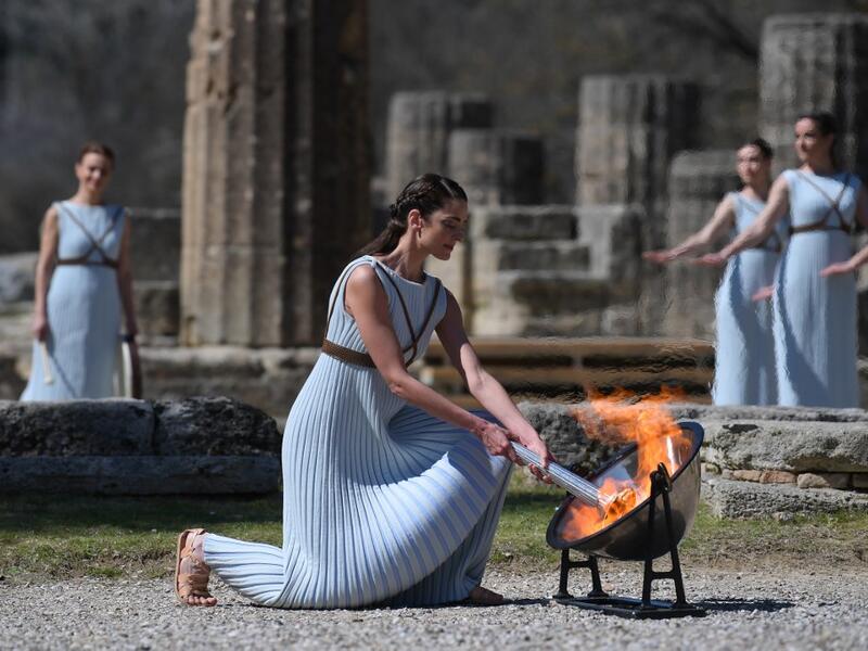 A woman dressed as a priestess lits the Olympic flame during the Olympic ceremony in ancient Olympia, ahead of Tokyo 2020 Olympic Games on March 12, 2020. ARIS MESSINIS / AFP