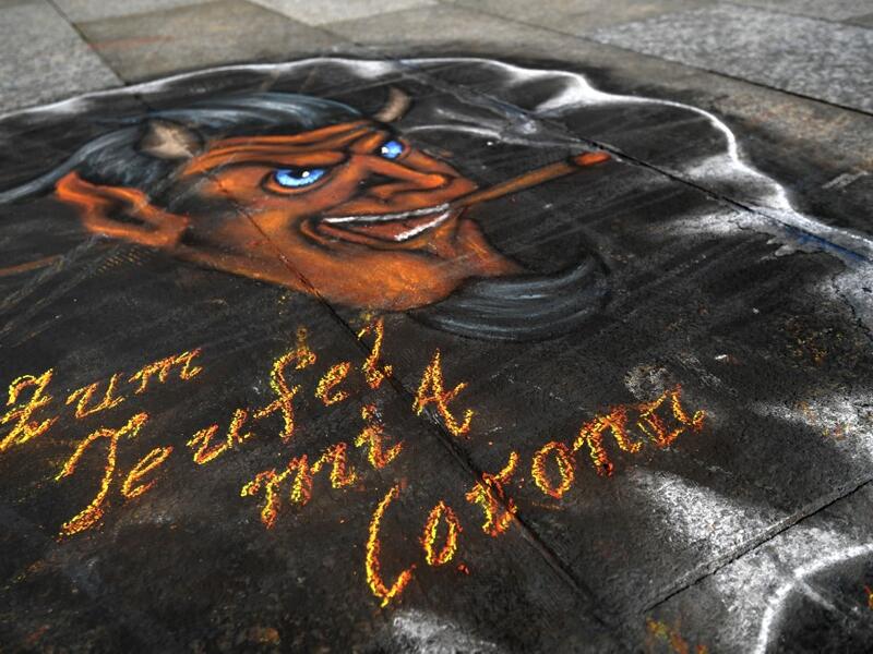 A graffiti 'to hell with corona' is seen in front of the Cologne cathedral on March 17, 2020, western Germany, where restaurants closed, as well as many activities slowed down or came to a halt due to the spread of the novel coronavirus. Ina FASSBENDER / AFP